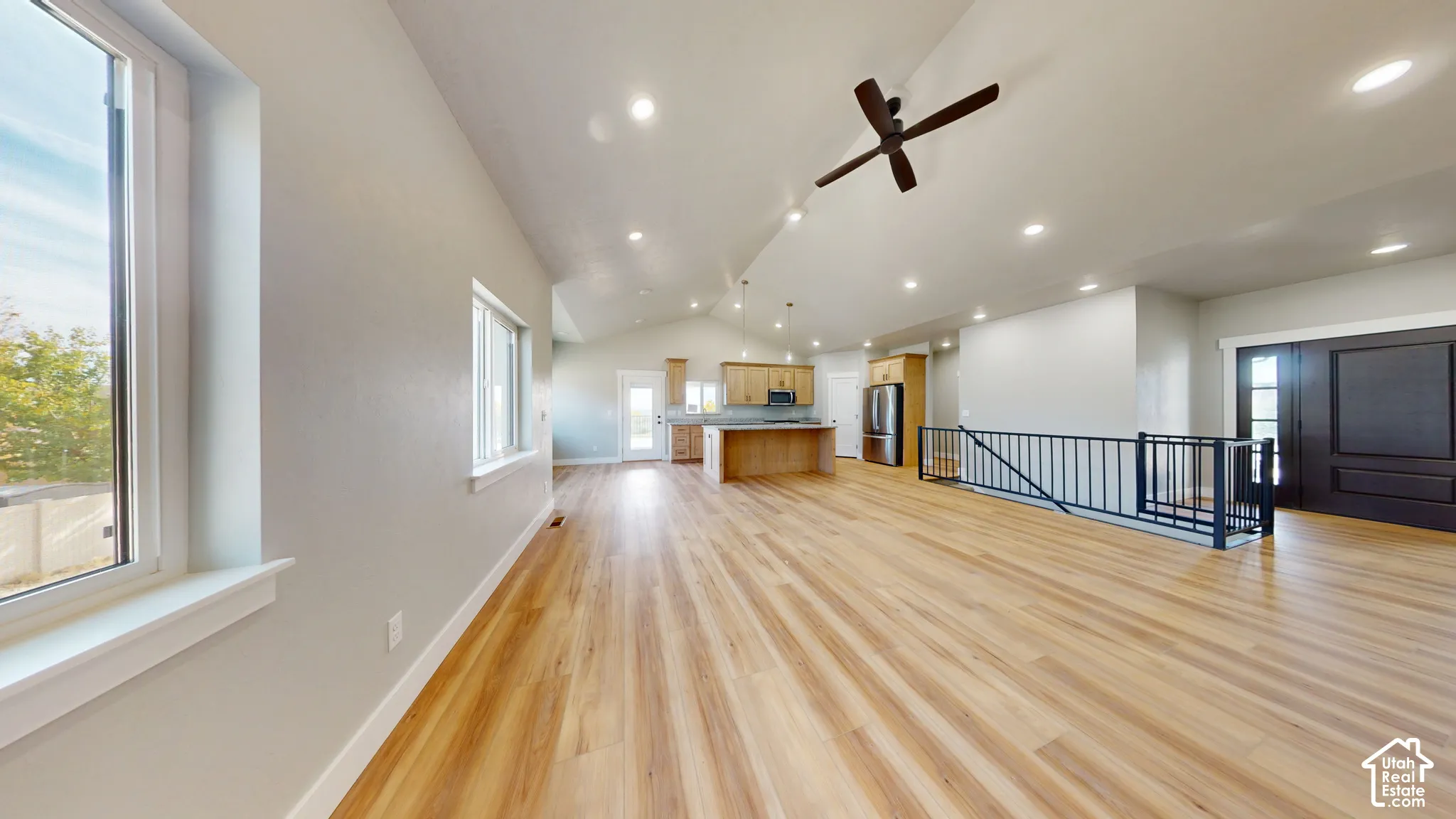 Open-concept interior featuring vaulted ceilings, wood-finish flooring, recessed lighting, and a kitchen equipped with a center island and wood-finish cabinetry
