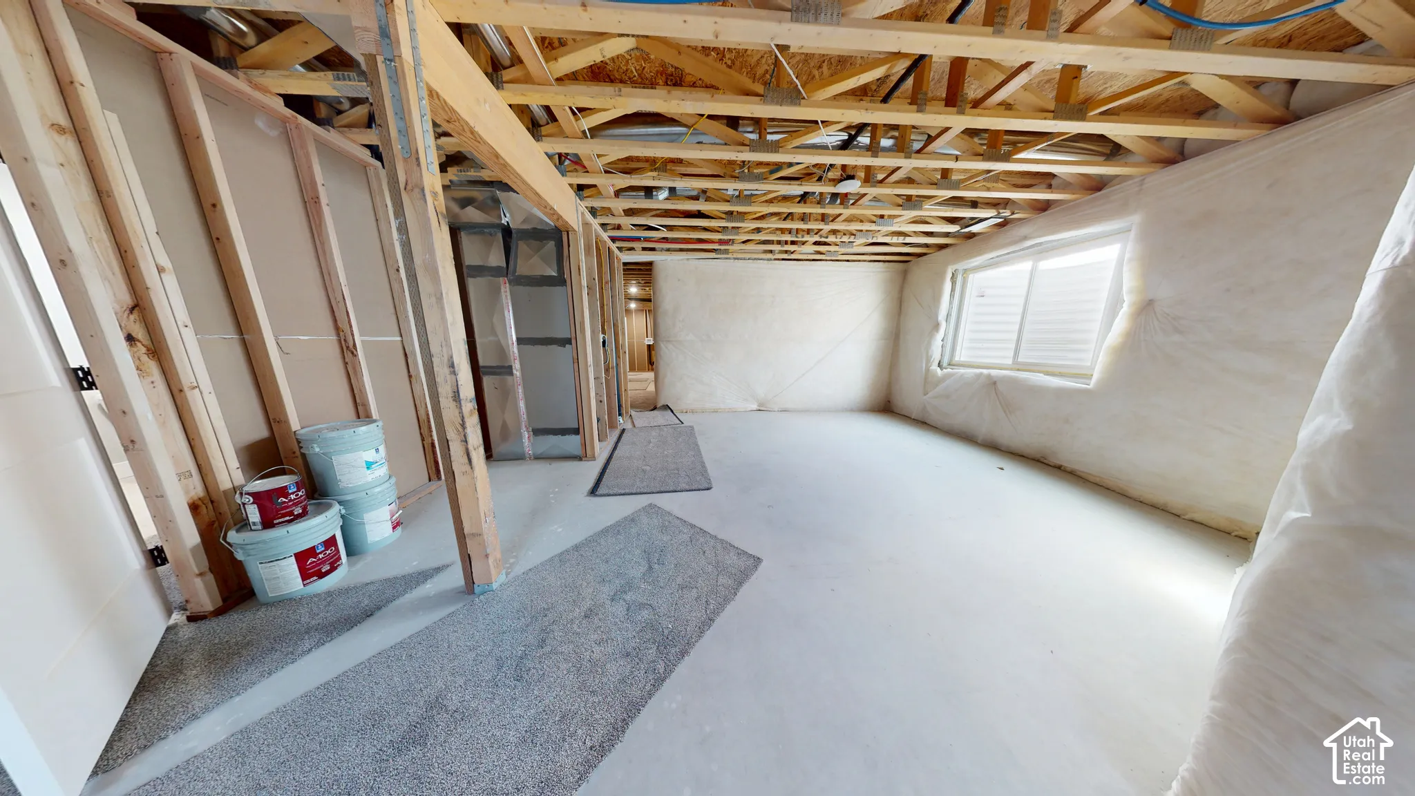 Unfinished interior space featuring exposed wood-truss ceiling framing, insulated wall panels, concrete flooring, and a single sliding window