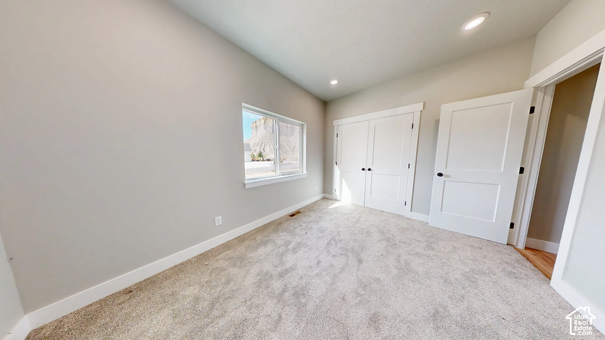 Interior space featuring neutral wall tones, carpeted flooring, recessed lighting, double-panel closet doors, and a single-pane window