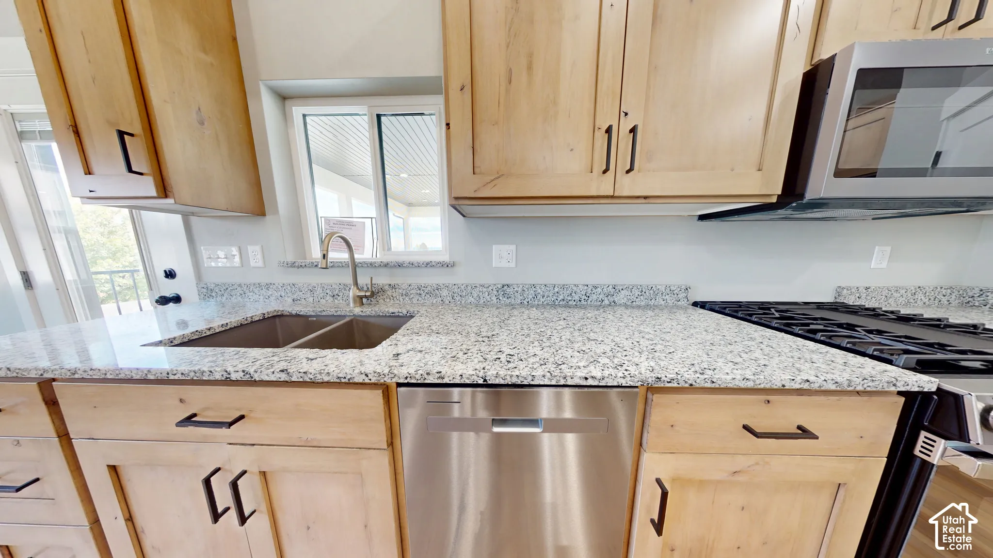 Kitchen featuring light-finish wood cabinetry, stone countertops, stainless steel undermount double-basin sink, gooseneck faucet, and stainless steel dishwasher
