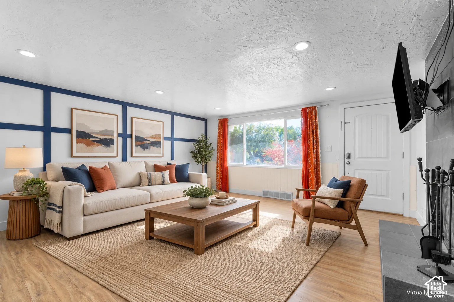 Living room featuring decorative wall molding, wood-finish flooring, recessed lighting, and a stone-surround fireplace