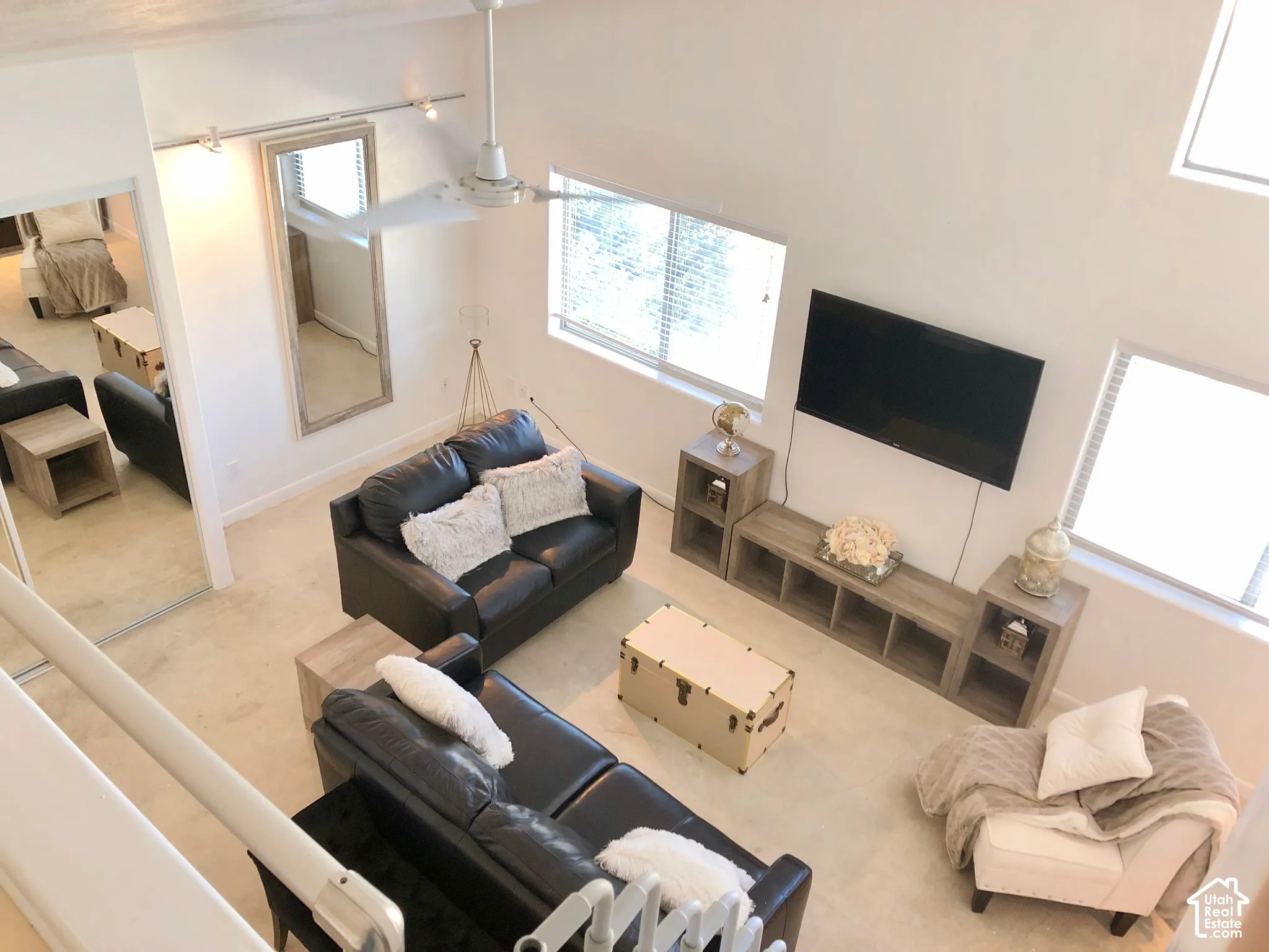 Vaulted ceiling with a white dual-blade ceiling fan, expansive natural lighting, and multi-level window configuration