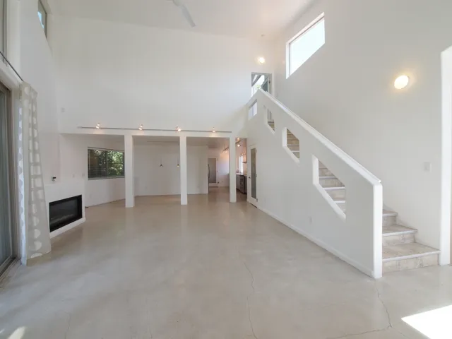 Vaulted ceilings with recessed lighting, polished concrete flooring, built-in fireplace, and staircase with geometric cutouts