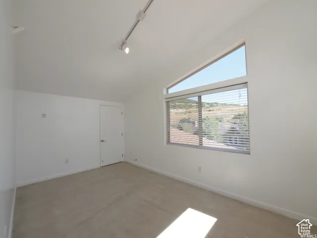 Vaulted ceiling featuring track lighting and a large trapezoidal window configuration