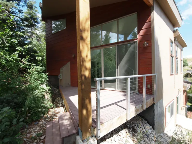 Exterior deck with cable railing, wood siding, large floor-to-ceiling glass sliding doors, and expansive transom windows