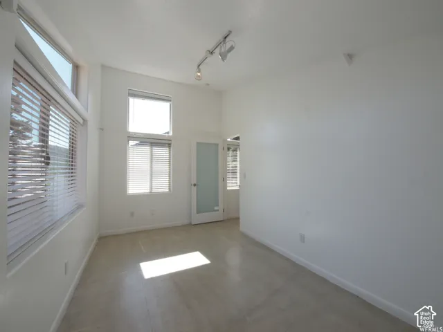 High ceilings featuring adjustable track lighting, large multi-pane windows, and a frosted glass door
