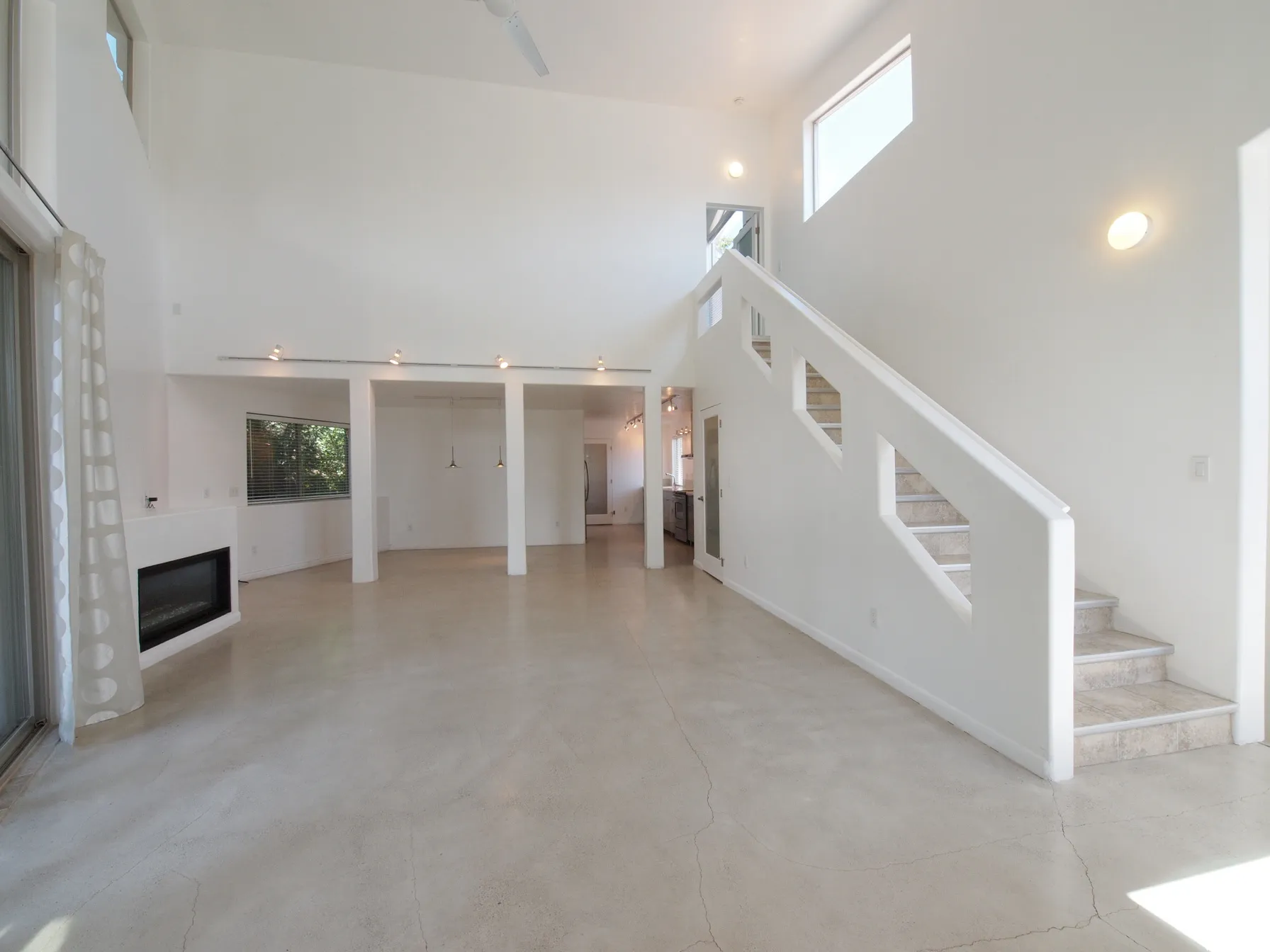 Vaulted ceilings with recessed lighting, polished concrete flooring, built-in fireplace, and staircase with geometric cutouts