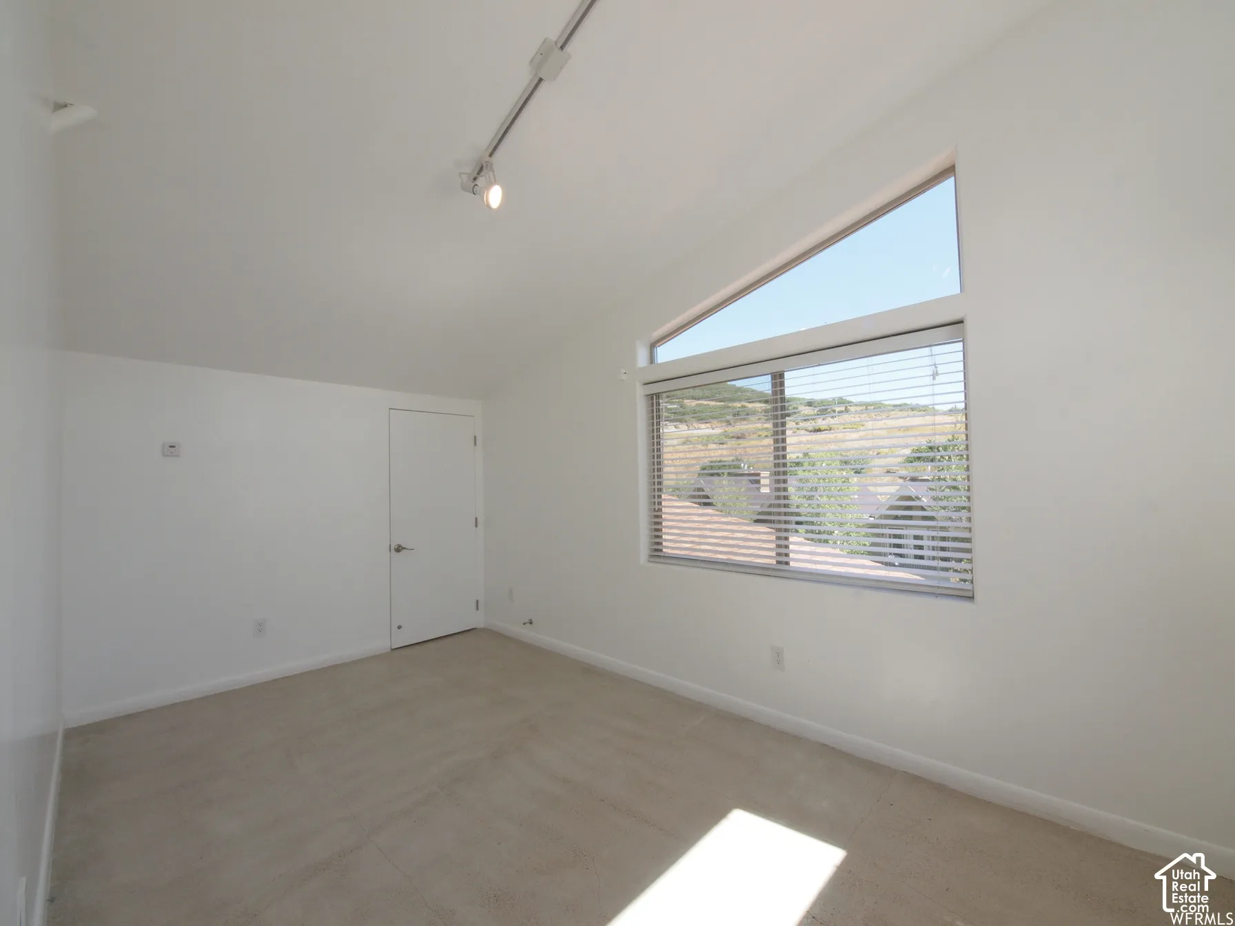 Vaulted ceiling featuring track lighting and a large trapezoidal window configuration