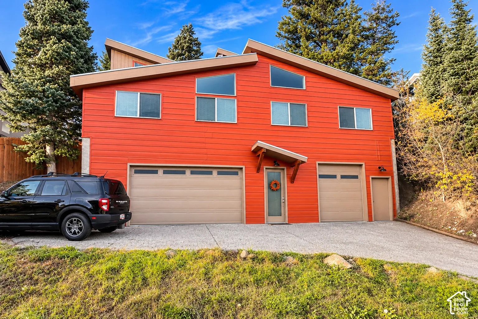 Multi-level exterior featuring horizontal lap siding, a shed roofline, two garage bays, and an expansive concrete driveway
