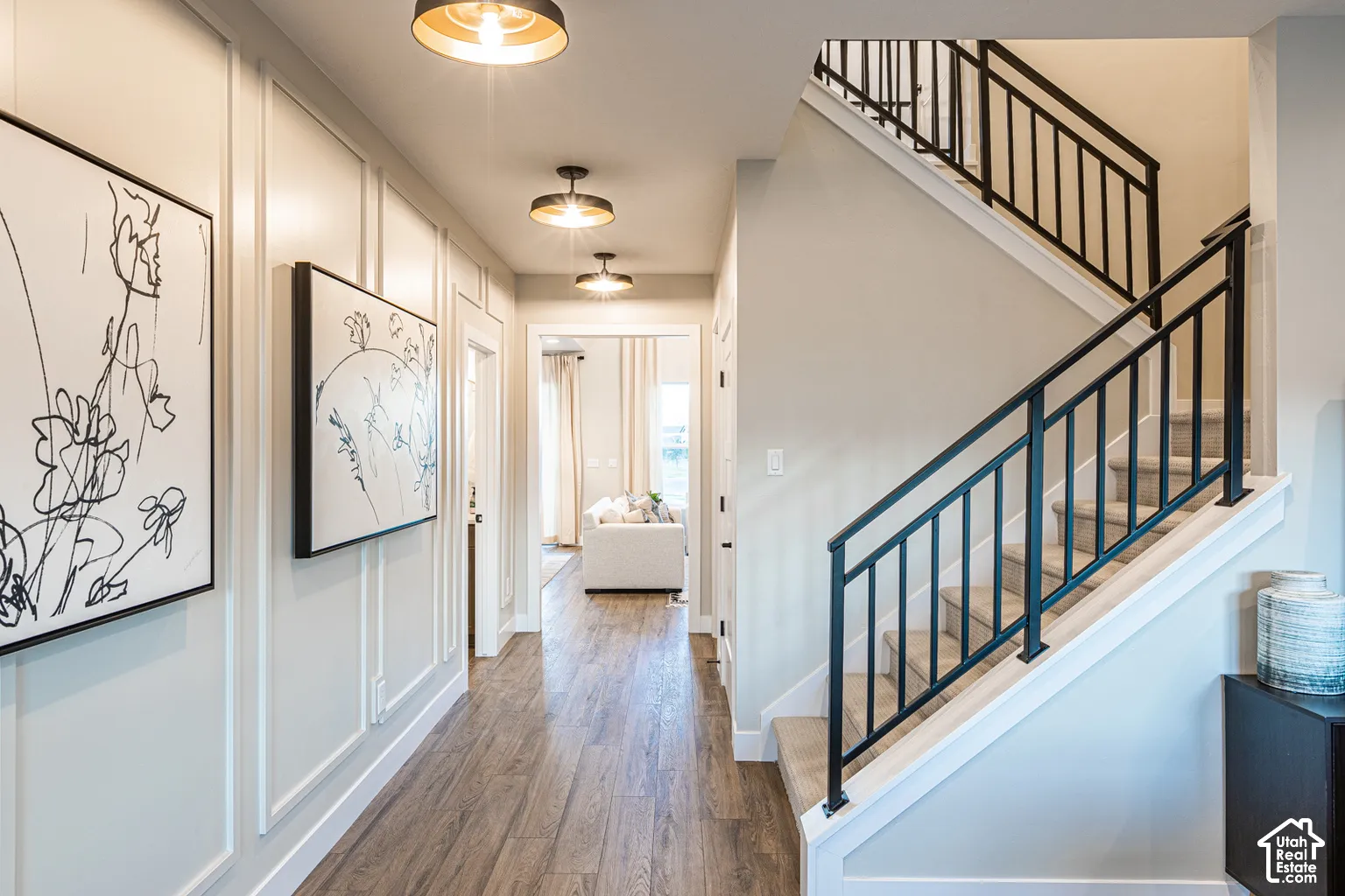 Entryway featuring wood-finish flooring, wall paneling, a staircase with metal railings, and industrial-style semi-flush mount lighting