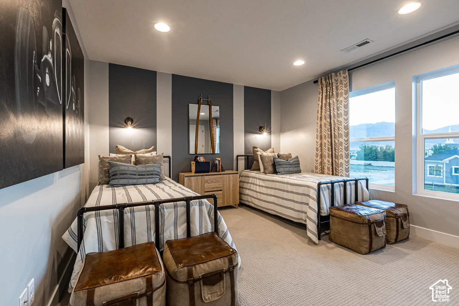 Room featuring dual wall-mounted light fixtures, textured carpet flooring, large windows with natural light, and accent wall detailing