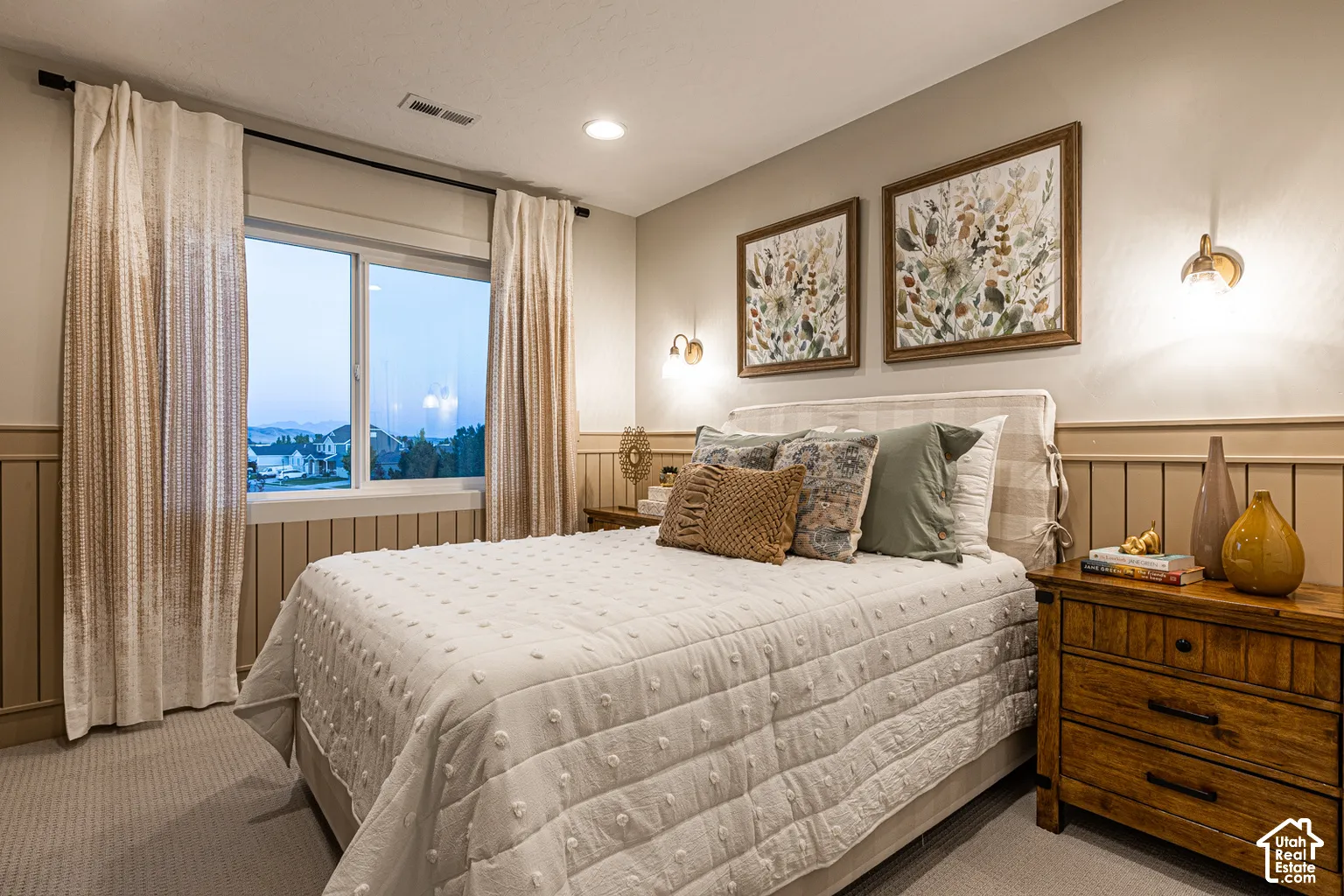 Neutral-toned room featuring wainscoting, wall-mounted light fixtures, and carpeted flooring