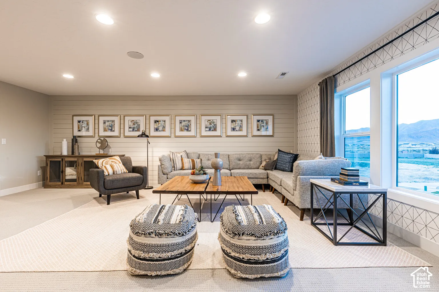 Living space featuring horizontal plank wall detailing, recessed ceiling lighting, patterned wall accents, and large windows with mountain backdrop