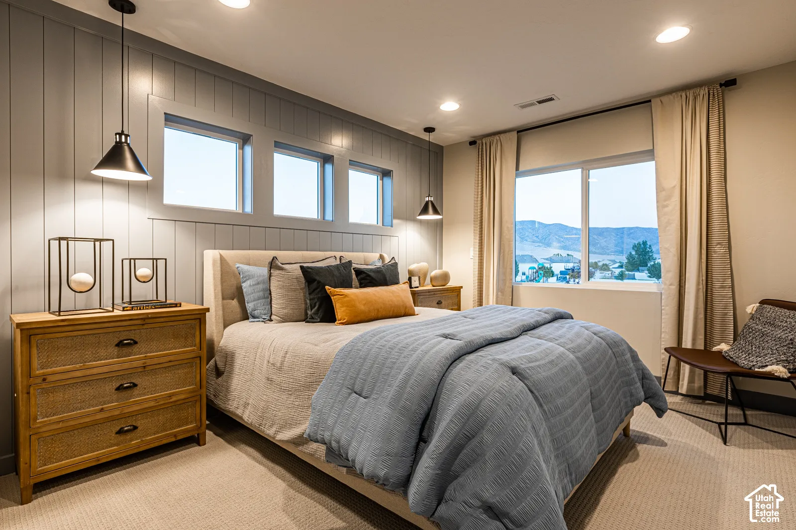 Vertical board-and-batten accent wall, recessed lighting, industrial-style pendant light fixtures, and windows with mountain scenery