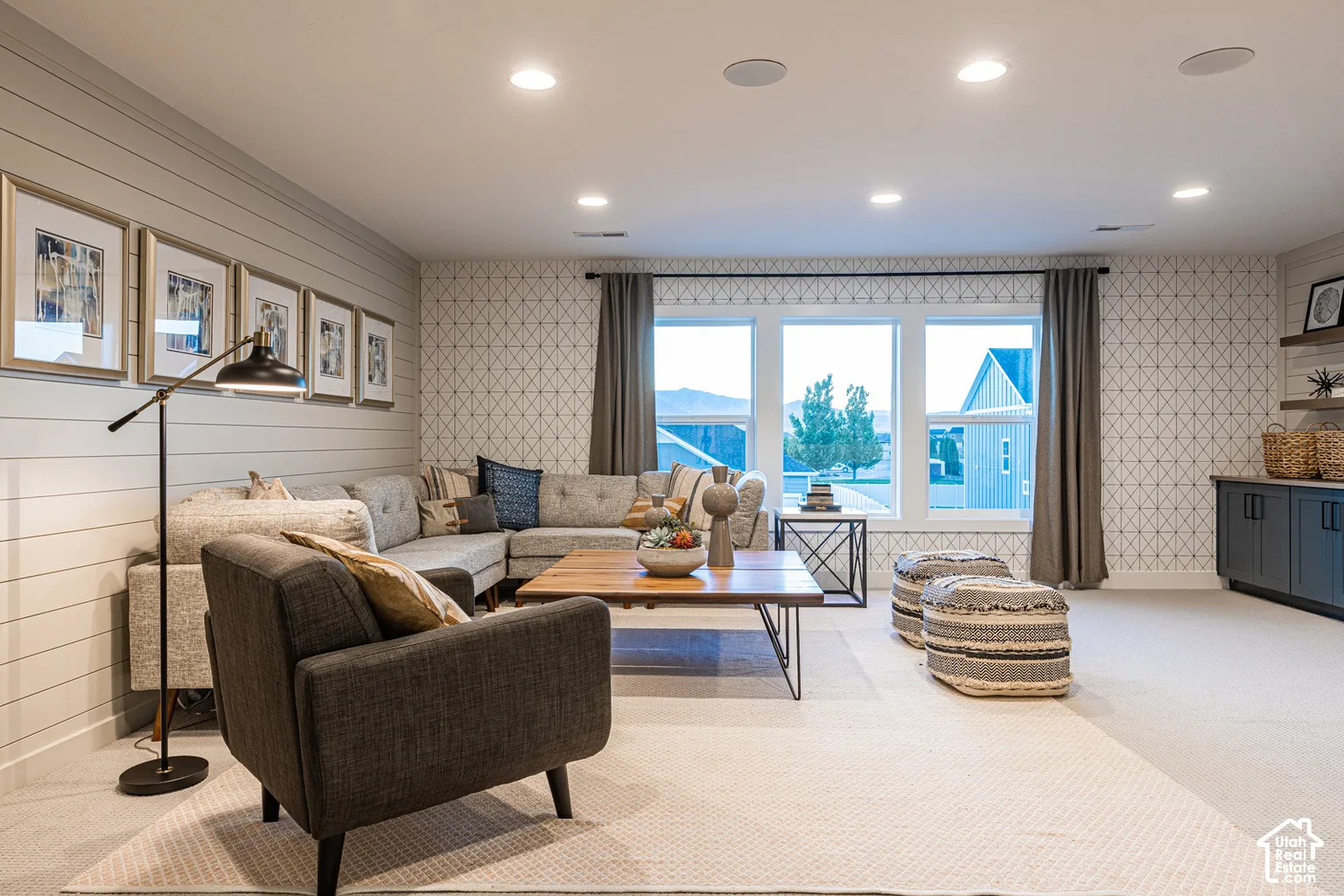 Horizontal shiplap wall paneling, geometric patterned wallpaper, recessed ceiling lighting, triple-pane window configuration, and built-in lower cabinetry with shelving