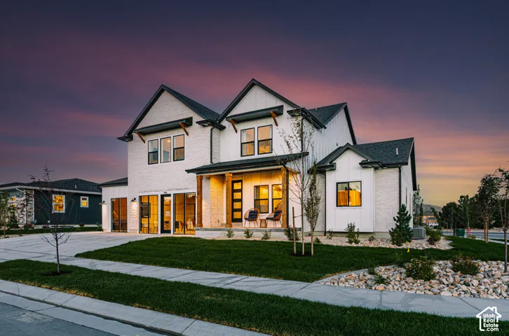 Modern exterior featuring white masonry and vertical siding, multi-gabled roofline, timber-post covered porch, and multi-pane garage doors