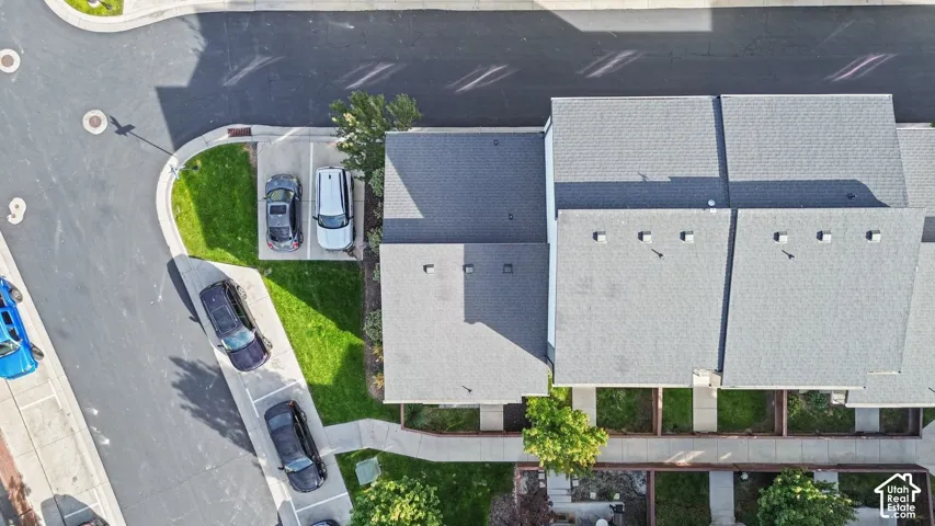 Aerial perspective featuring asphalt shingle roofing, paved driveways, concrete walkways, and landscaped lawn areas