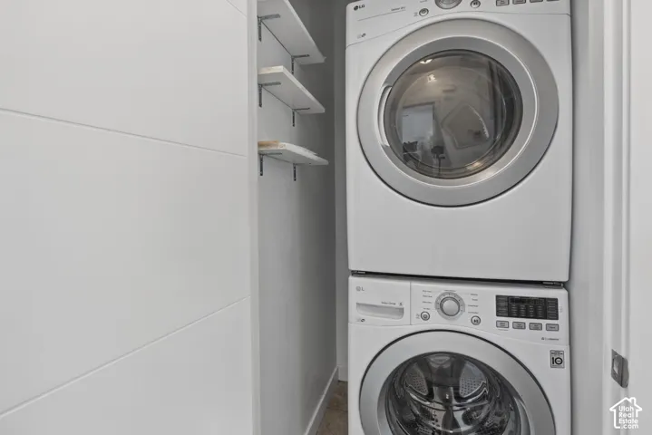 Stacked laundry unit featuring white front-load appliances and integrated wall-mounted shelving