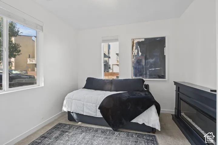 Interior space featuring neutral wall tones, carpeted flooring, two windows with integrated blinds, and a built-in dark-finish electric fireplace