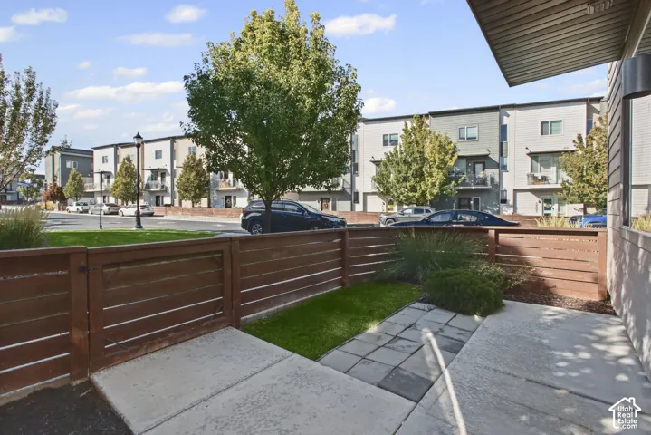 Private patio featuring horizontal wood fencing, concrete pavers, and a synthetic turf patch