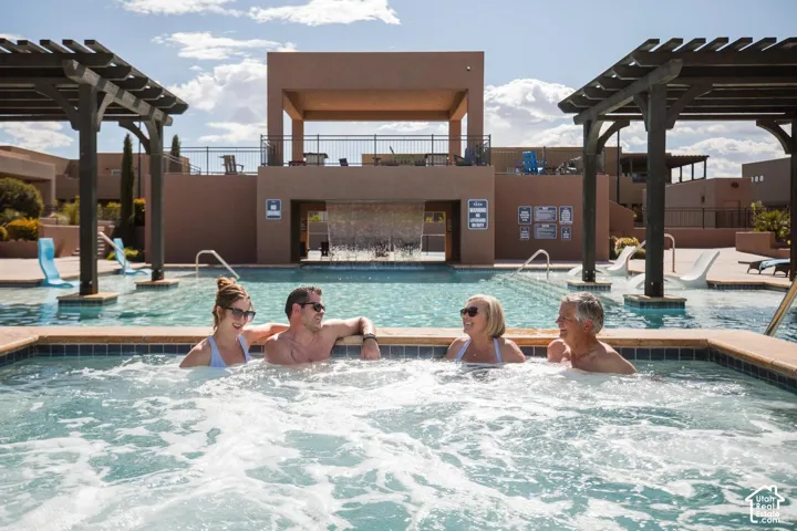 Swimming pool featuring a tiered water feature, integrated spa, and dual wooden pergolas