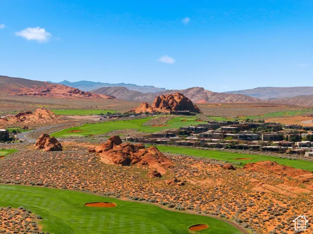Aerial perspective showcasing expansive green golf course fairways integrated with natural red rock desert landscape and mountain ranges