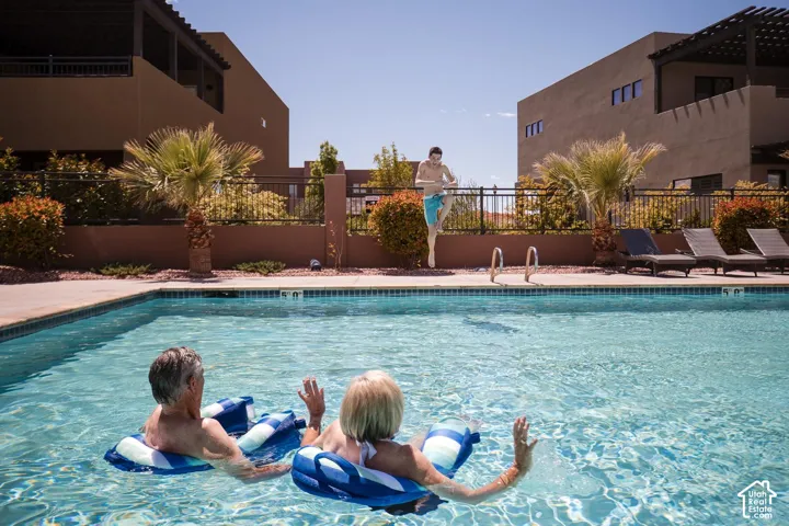 Swimming pool featuring a concrete deck, metal perimeter fencing, and desert landscaping