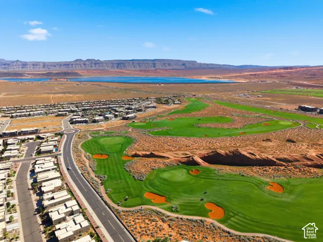 Aerial perspective showcasing a sprawling golf course, native desert landscape, reservoir, and mountain backdrop