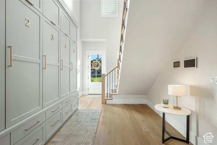 Built-in floor-to-ceiling cabinetry with metallic hardware, wood-finish flooring, and staircase featuring a wood handrail with metal balusters