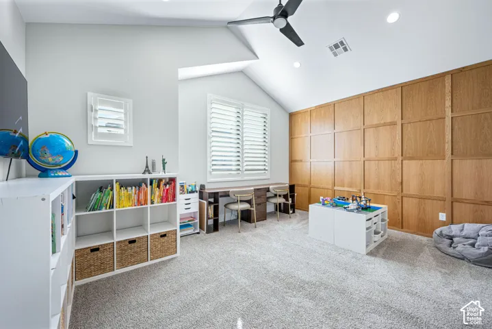 Vaulted ceiling featuring a wood-panelled accent wall, recessed lighting, a modern ceiling fan, and plantation shutters