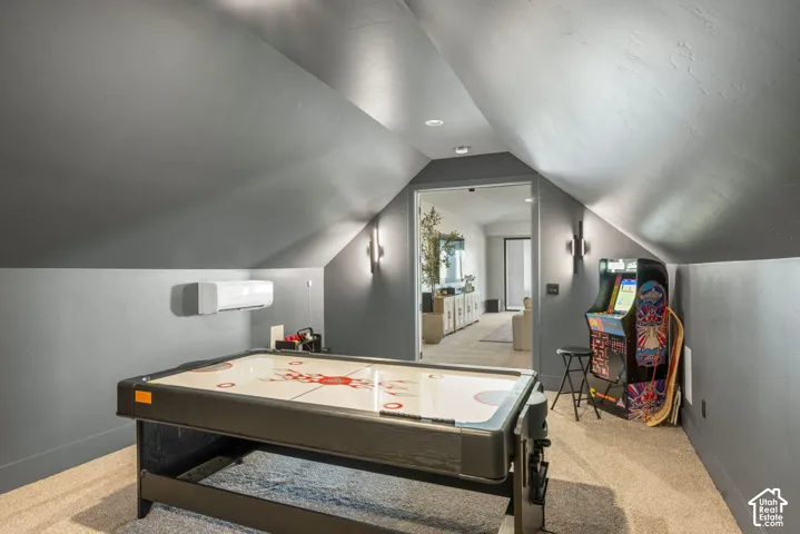 Vaulted ceilings with recessed lighting, wall-mounted ductless heating and cooling unit, and modern vertical wall-mounted sconces