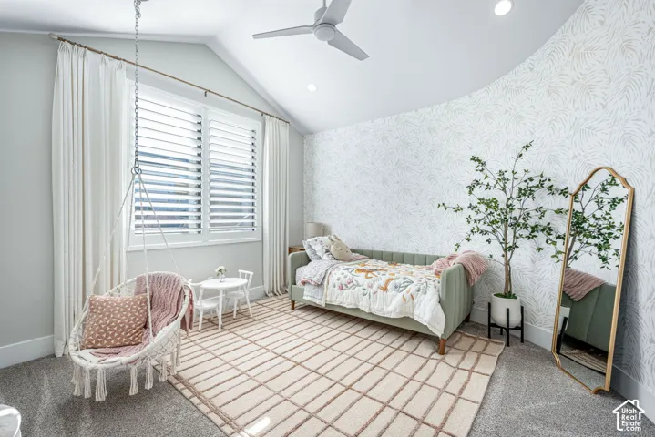 Vaulted ceiling with a matte white modern ceiling fan, large window with plantation shutters, and patterned accent wall