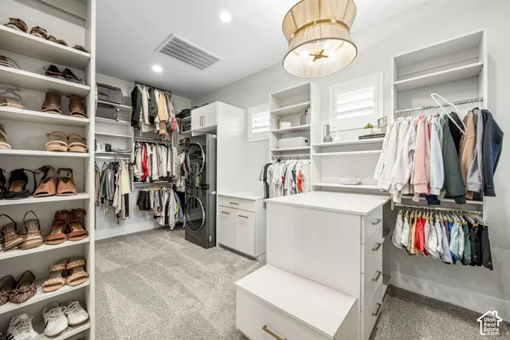 Custom walk-in closet featuring floor-to-ceiling built-in shelving, integrated laundry center, central island with storage drawers, and recessed lighting