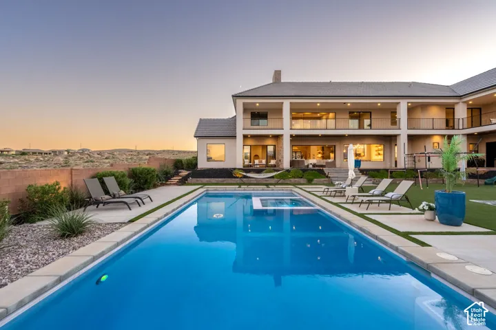 In-ground swimming pool with built-in spa, dual-level covered patio, and concrete hardscaping
