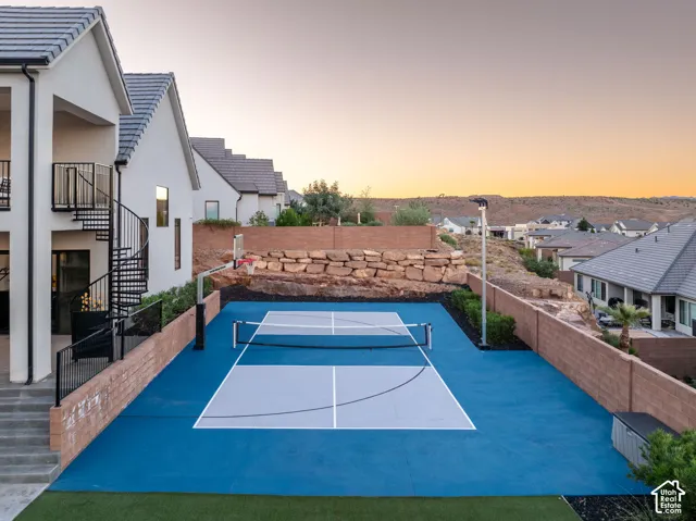 Sport court with synthetic surfacing and perimeter masonry walls, complemented by a spiral metal staircase and covered patio space