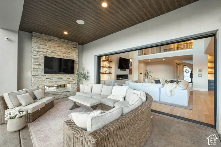 Covered patio featuring a floor-to-ceiling stone fireplace, recessed ceiling lighting, and a multi-panel sliding glass door system
