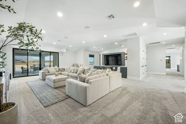 Open-concept floor plan featuring recessed lighting, vaulted ceilings, neutral wall tones, large-format sliding glass doors, and a custom built-in media wall