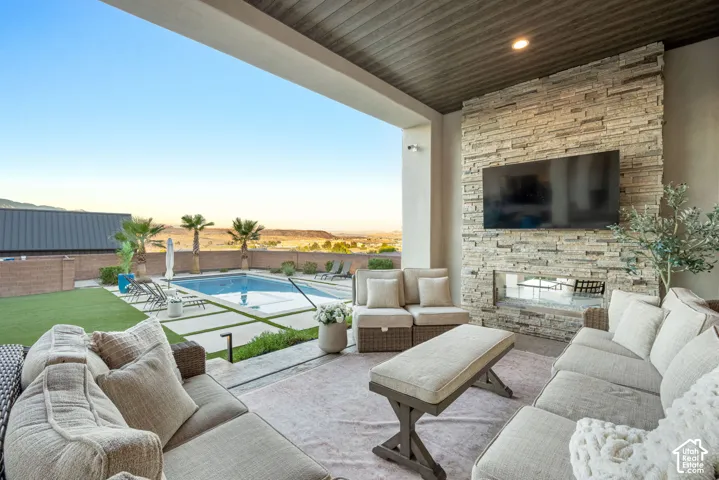 Covered patio featuring a stacked stone fireplace, tongue-and-groove wood ceiling, built-in television mount, in-ground swimming pool, and paver hardscaping