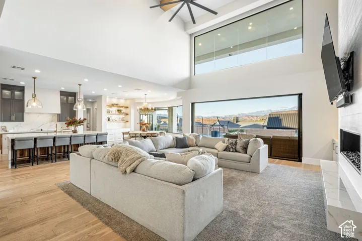 Vaulted ceilings, large-format sliding glass walls, built-in fireplace with stone surround, wood-finish flooring, and recessed lighting