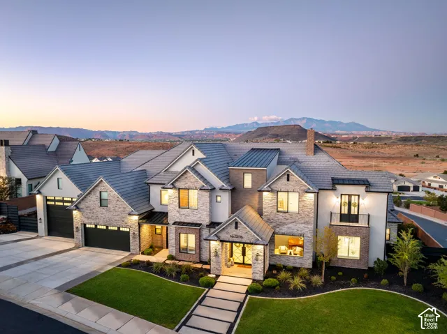 Custom multi-gabled exterior featuring stone masonry and light-toned siding, concrete tile roofing, metal accent awnings, and an attached three-car garage
