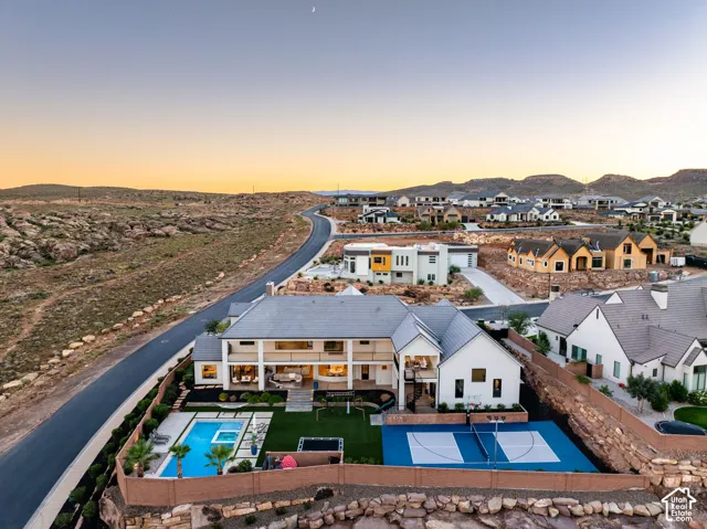 Exterior grounds featuring a custom swimming pool with integrated spa, synthetic turf lawn, multi-sport hard court, and fenced perimeter