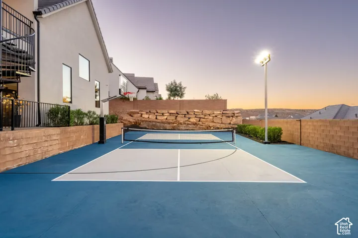 Private sports court featuring a multi-sport surface, integrated basketball hoop, perimeter masonry retaining walls, and stadium-style overhead lighting