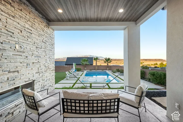 Covered patio featuring a stacked stone accent wall, recessed lighting, wood-finish ceiling, inground pool, and concrete paver patio with turf inlays