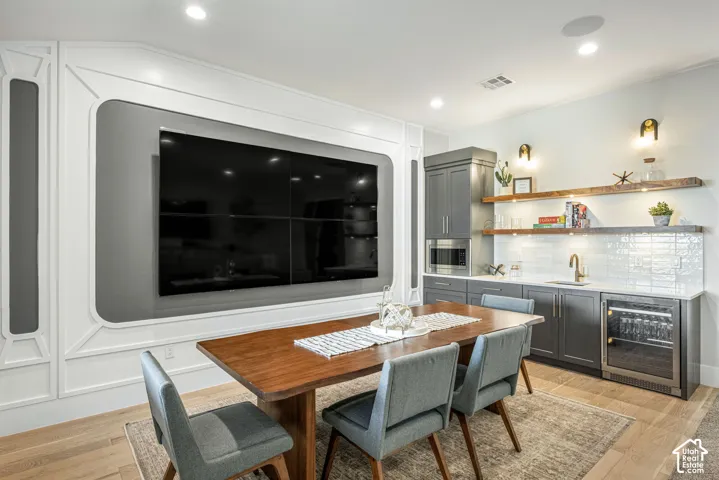 Custom millwork accent wall, built-in cabinetry with integrated beverage refrigerator, stone countertops, undermount sink, and wood-finish flooring