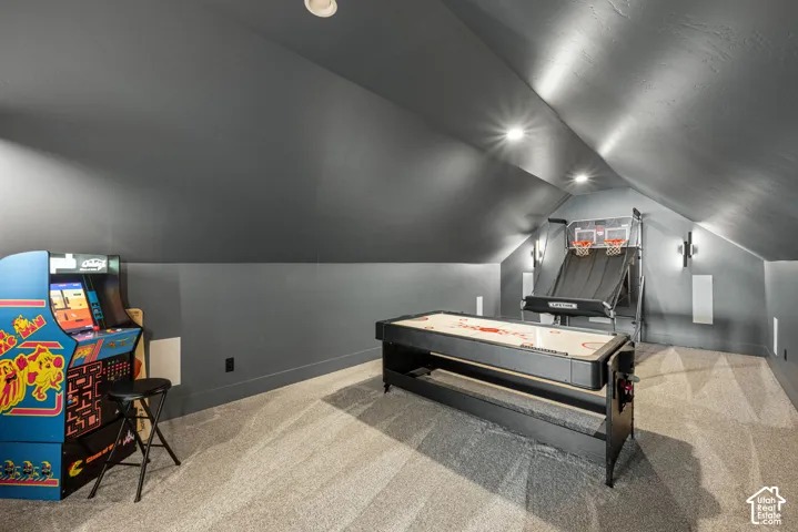 Finished room featuring vaulted ceilings, recessed lighting, wall-mounted light fixtures, and wall-to-wall carpeting