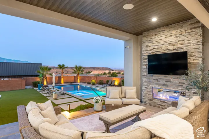 Covered patio featuring a stacked stone fireplace, tongue-and-groove ceiling, recessed lighting, and a built-in swimming pool with a surrounding concrete paver deck