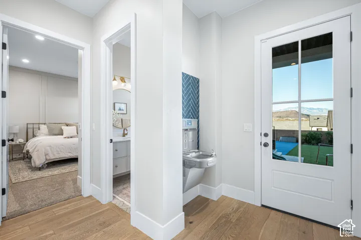 Full-light glass exterior door, wood-finish flooring, built-in wall-mounted water fountain with blue herringbone tile backsplash, and mountain backdrop