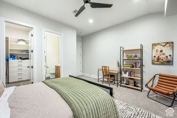 Bedroom featuring a matte black ceiling fan, neutral carpeting, and a built-in walk-in closet with integrated shelving and drawer storage