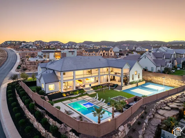 Multi-level residence featuring a tiered tile roof, private swimming pool with integrated spa, multi-sport court, and covered balconies