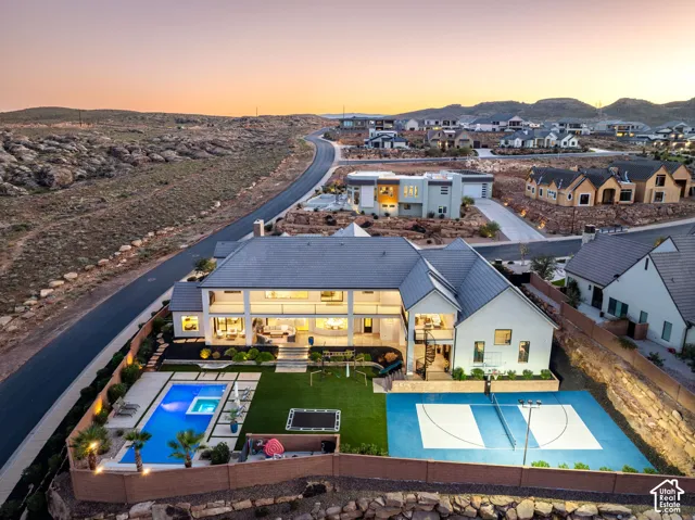 Multi-level residence featuring a swimming pool, integrated spa, sport court, synthetic turf lawn, and stacked-stone perimeter wall
